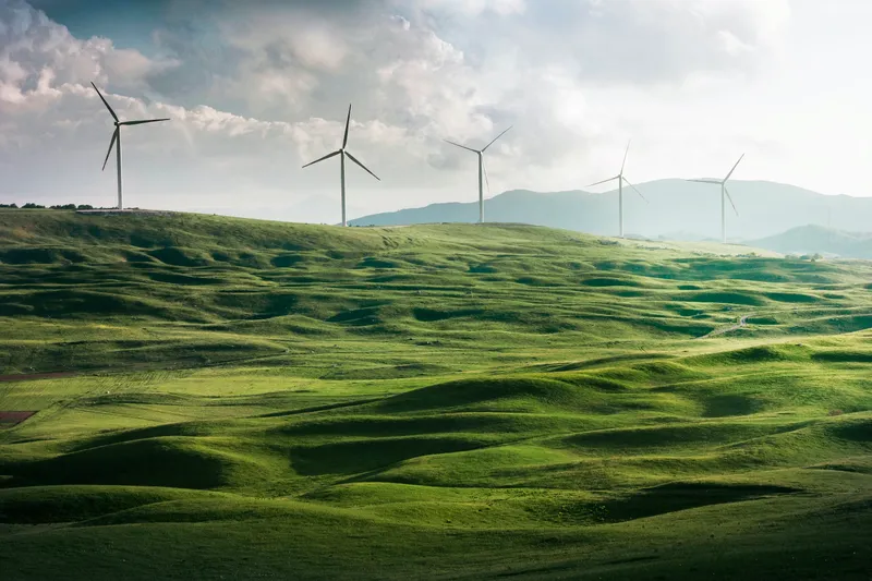 rolling green hills with wind turbines in the distance